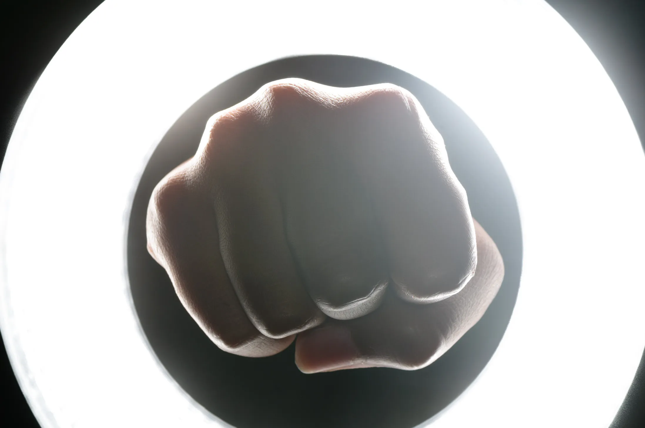 An illuminated fist punching through a circular light