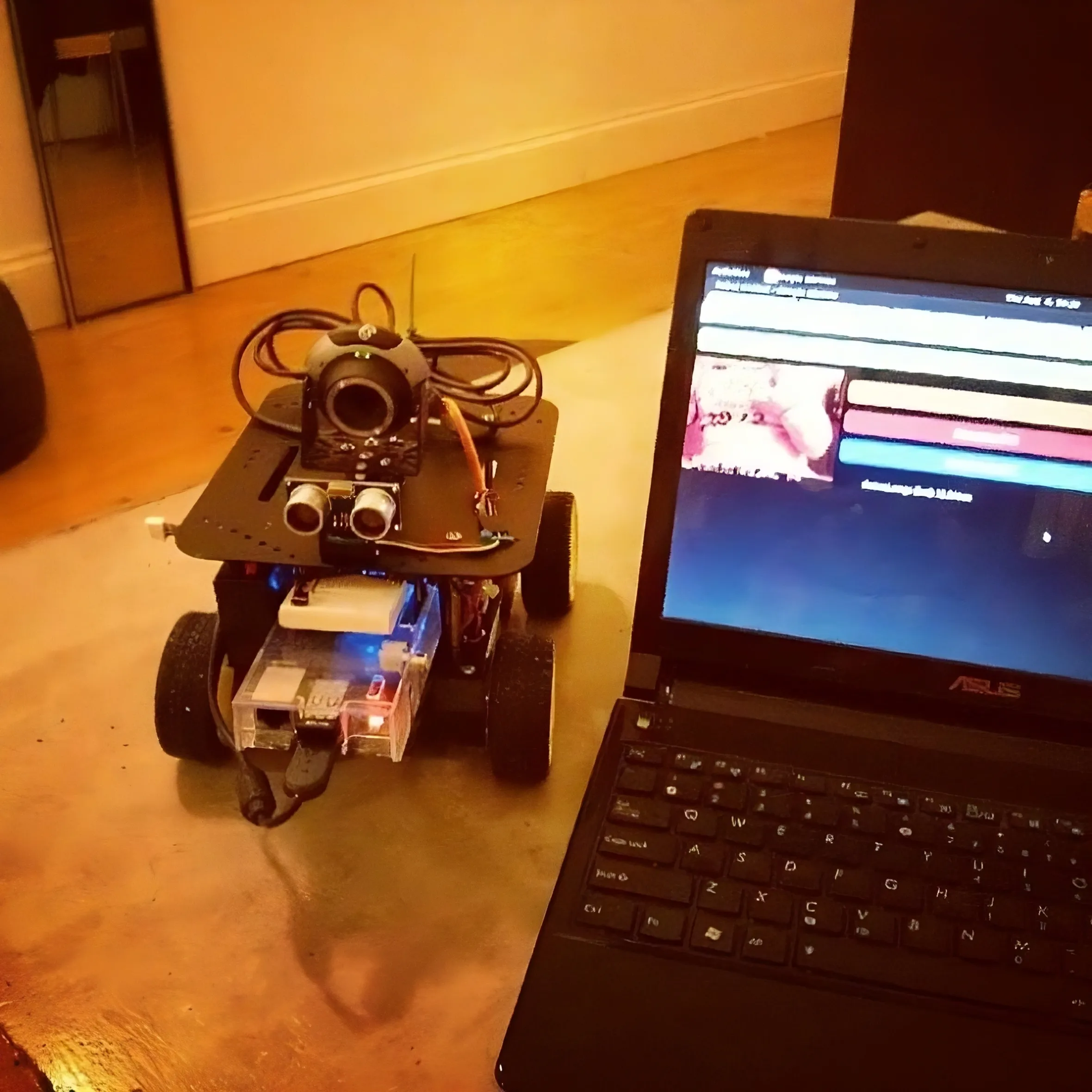 Small, wheeled robot next to laptop computer