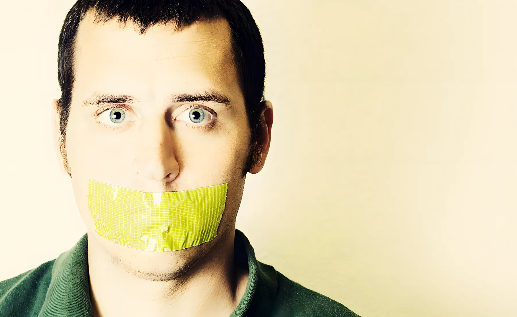 Dark haired man with mouth taped shut