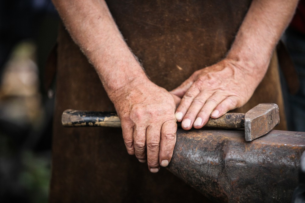 Photo of a blacksmith's hands on a hammer and anvil
